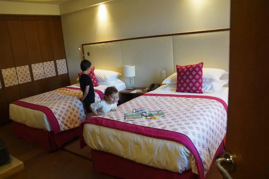 kids checking out the rooms at Sheraton grand Salzburg. Little boy looking down at some crayons and coloring books left at the bed with a big smile. Great family hotel in Salzburg