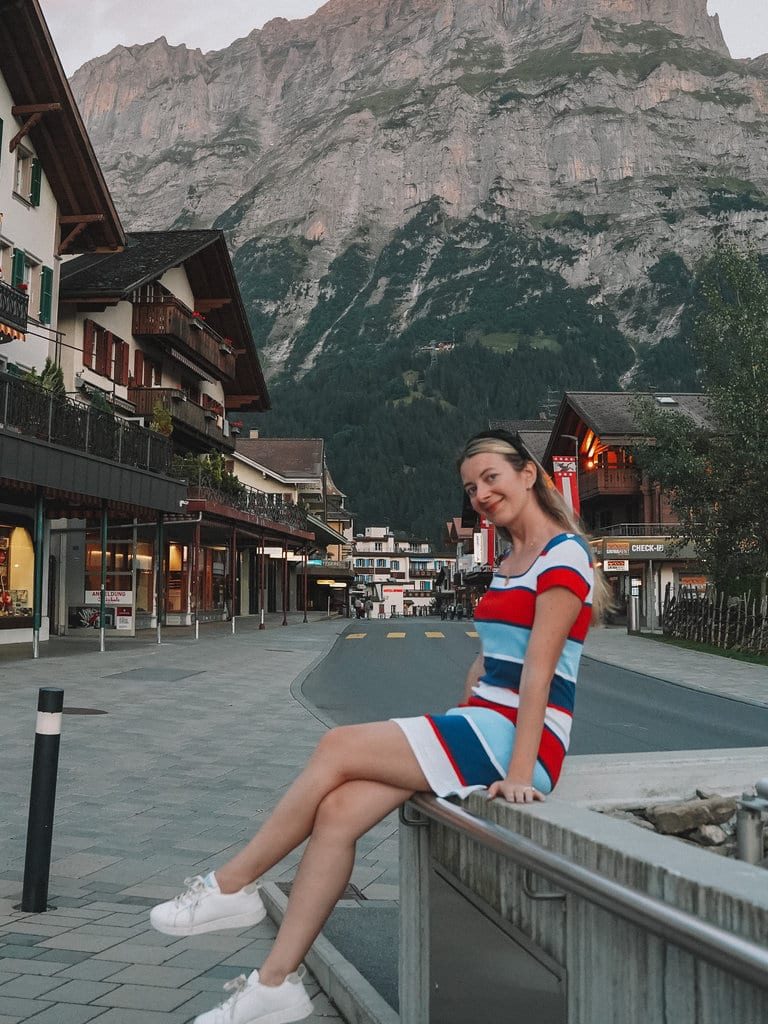 a woman in Grindelwald in striped dress and sneakers happily smiling at the camera 