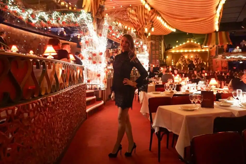 lady in a black short evening dress posing inside the Moulen Rouge Paris Cabaret Show dining area