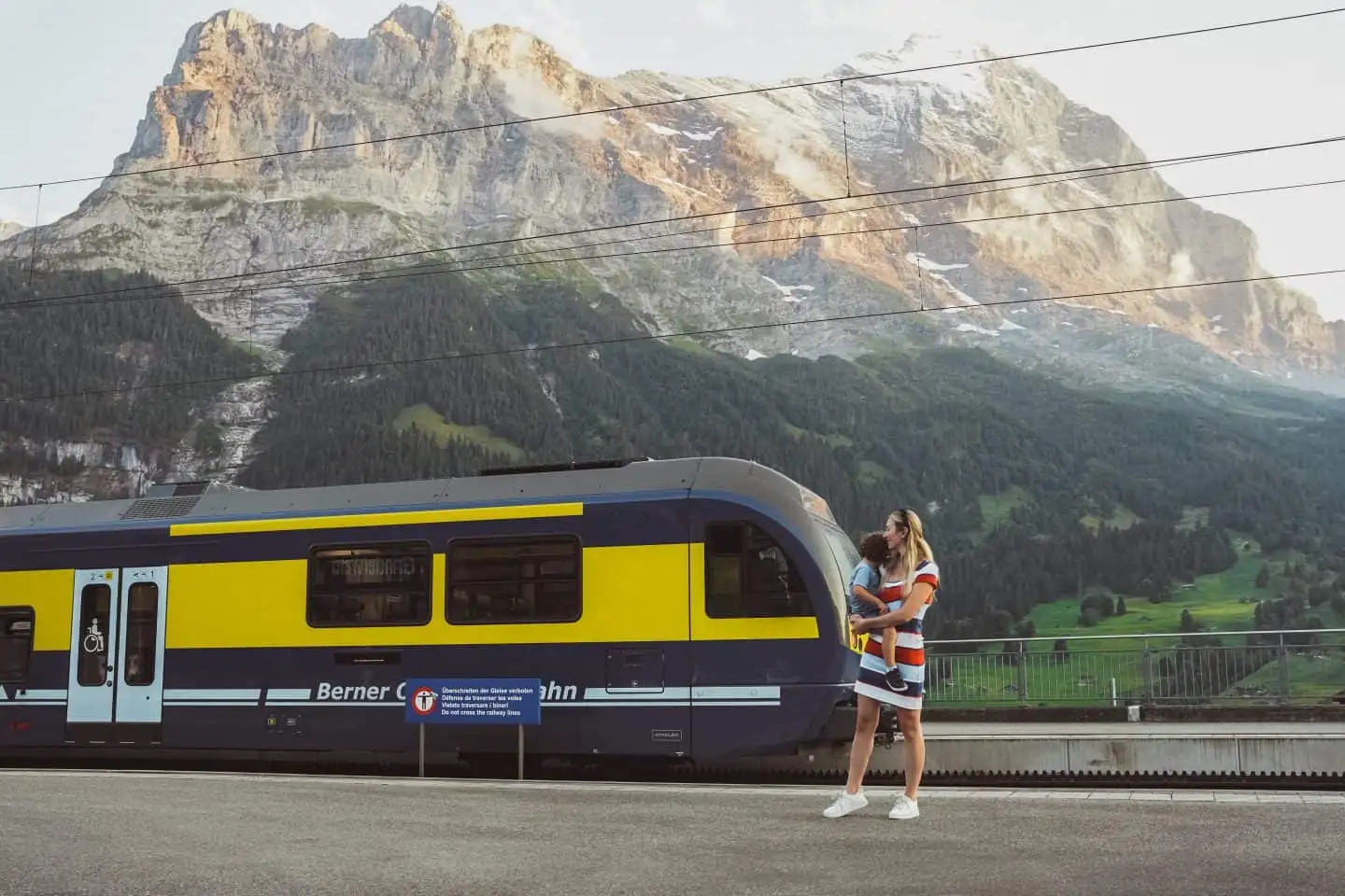 Mom holding a baby standing in front of Grindelwald train Station