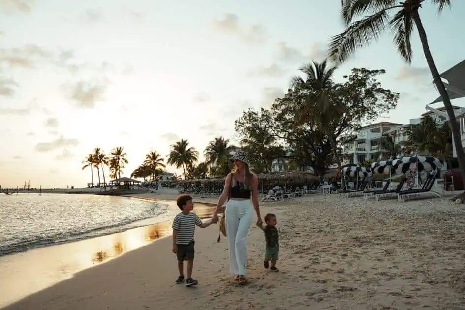 mom holding hands of two kids each side walking smiling on the beach in St Lucia