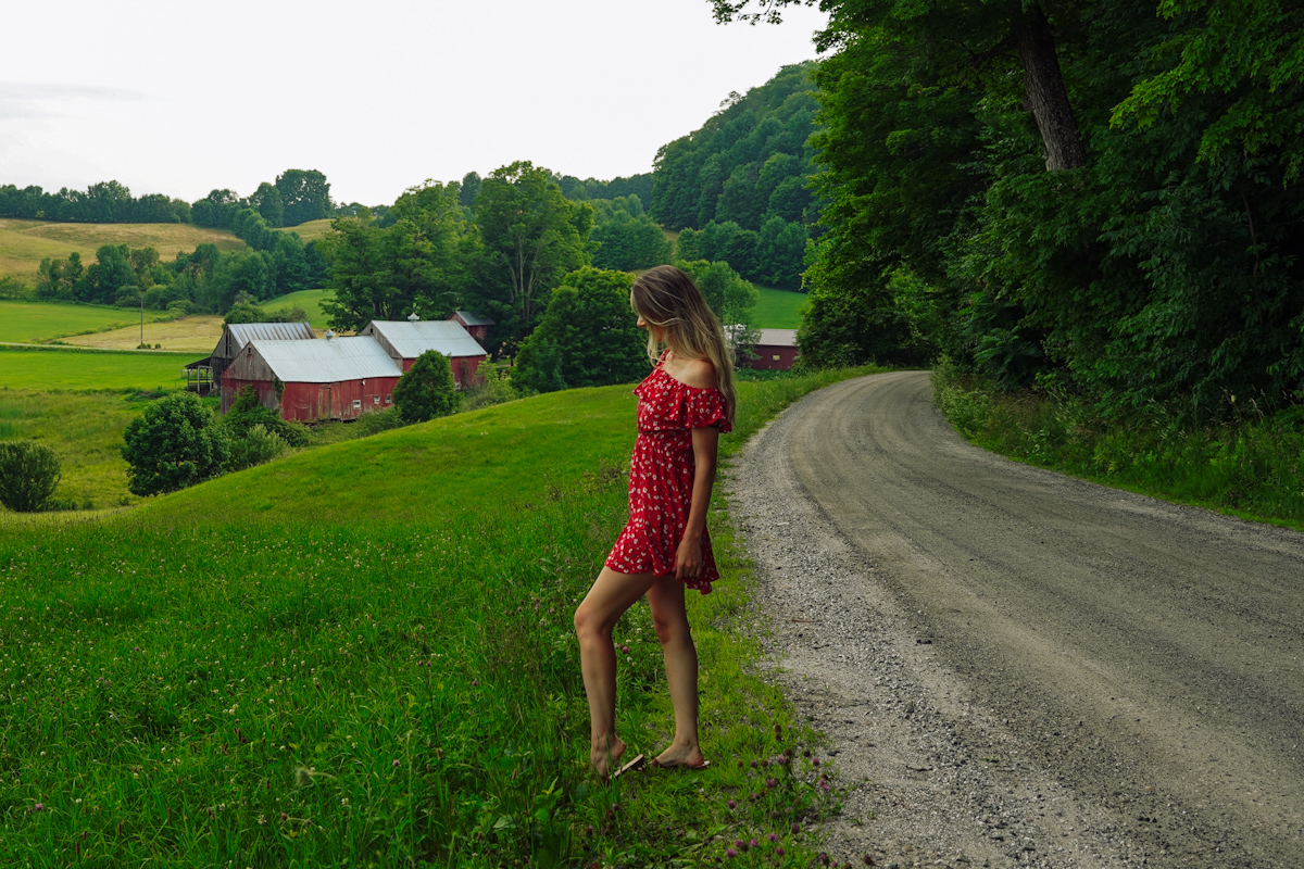 A girl in Red short dress standing in front of a red burn in Woodstock, Vt